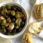 White bowl with olives, bread , white beige background