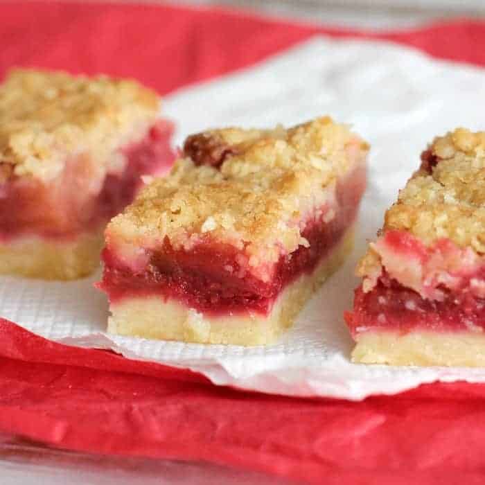 Close-up of raspberry apple bars on white and red napkins.