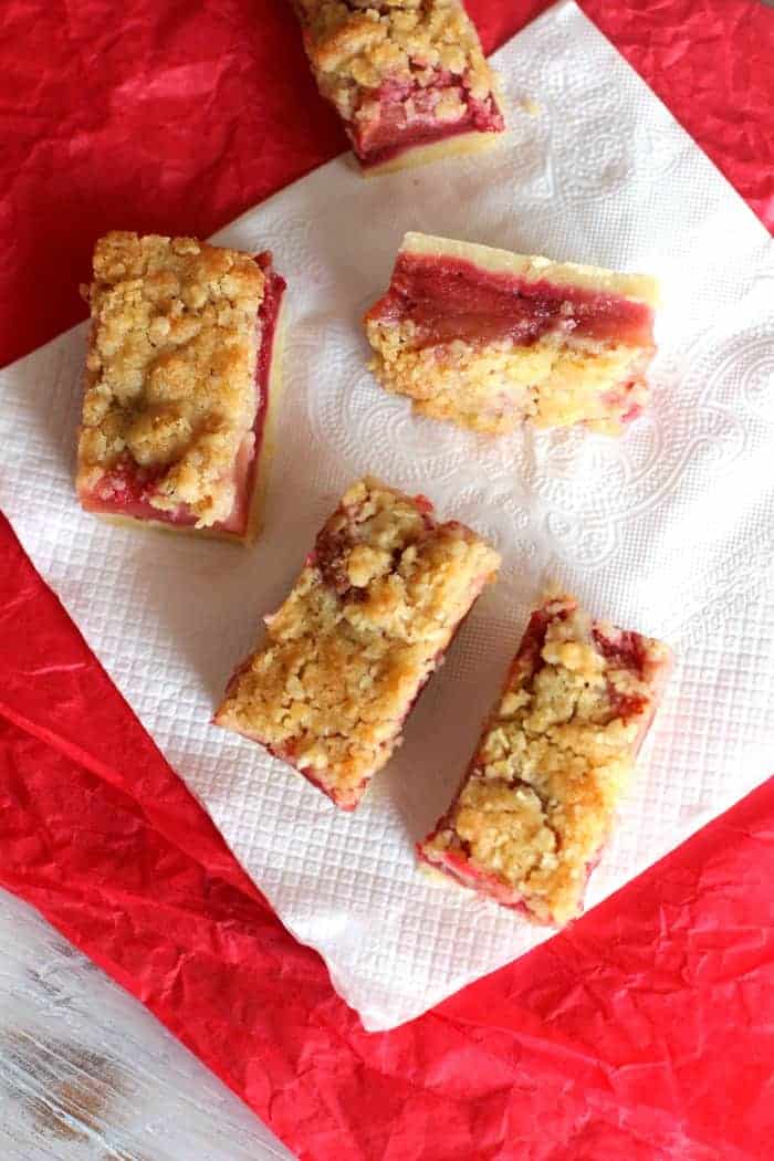 Several rectangles of raspberry apple crumb bars on red and white napkins.