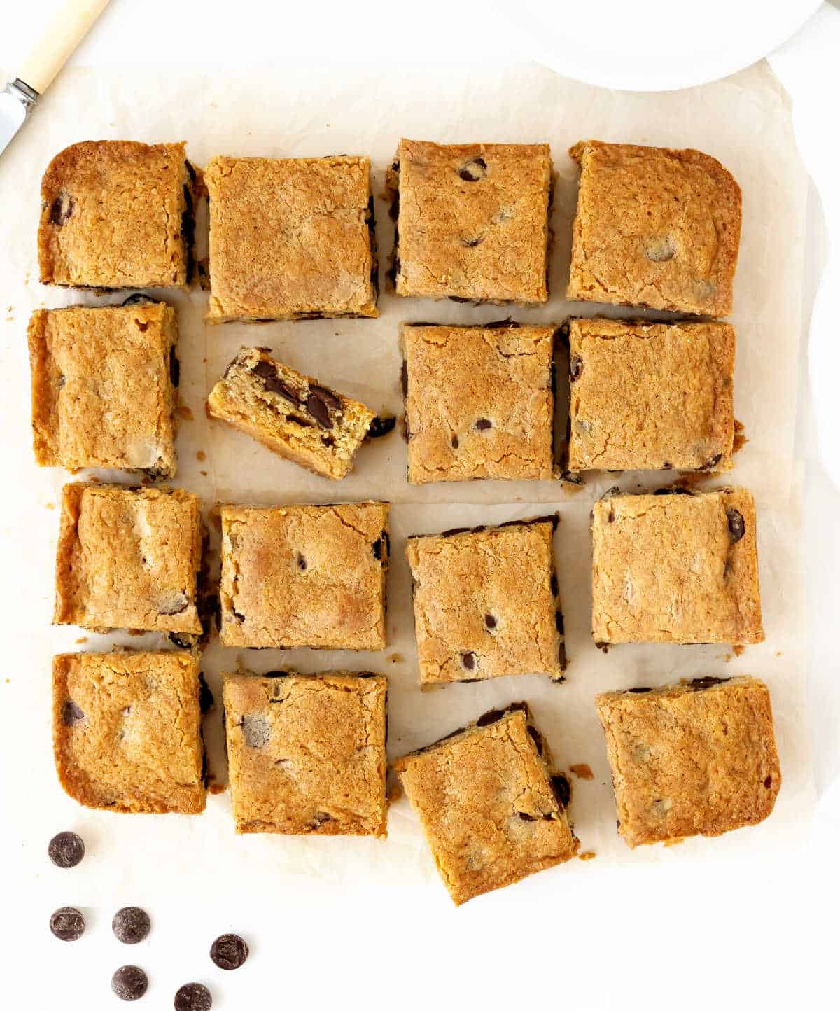 Top view of chocolate chip blondies squares on a whitish surface.