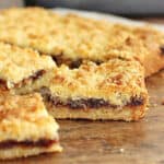 Wooden table with several squares of filled shortbread.