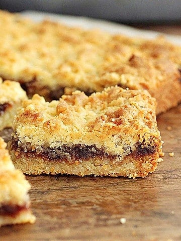 Wooden table with several squares of filled shortbread.