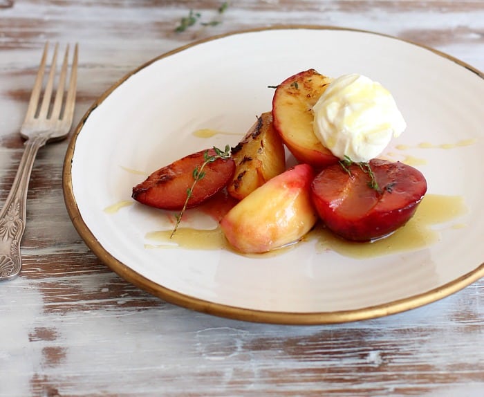 Honey Stone Fruit with thyme, cream and olive oil on white plate, fork