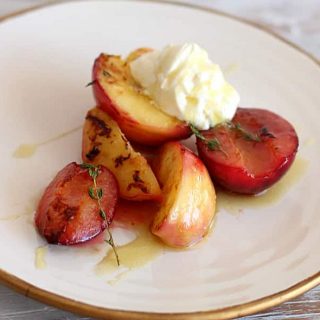 White and gold plate with stone fruit, cream and honey