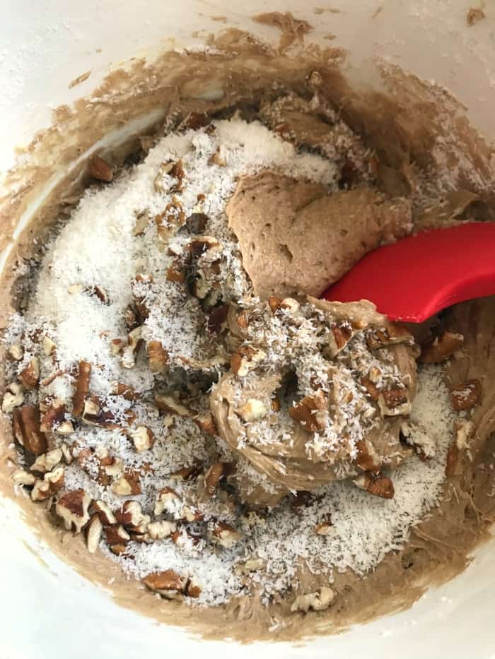 Coconut pecan loaf cake batter in a white bowl with a red spatula. 