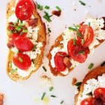Slices of toast with tomatoes and ricotta cheese on a wooden surface