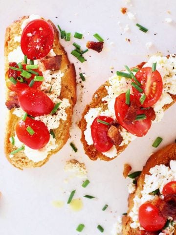 Slices of toast with tomatoes and ricotta cheese on a wooden surface