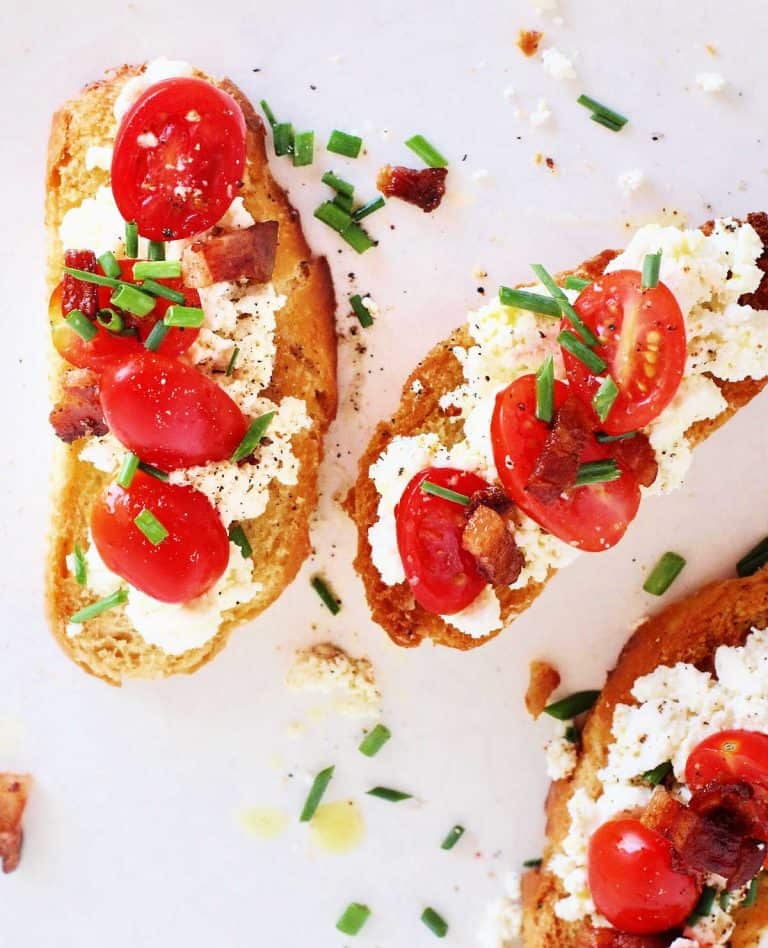 Slices of toast with tomatoes and ricotta cheese on a wooden surface