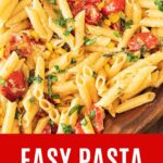Red, white and yellow text overlay on close up short pasta with tomatoes, corn and herbs.
