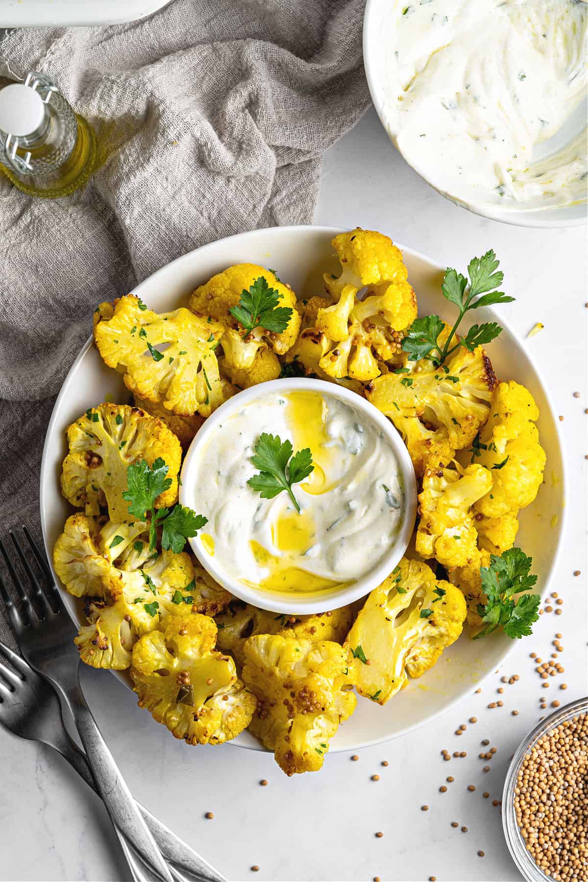 Platter of roasted cauliflower bites with yogurt dip. Top view. Gray background and towel.