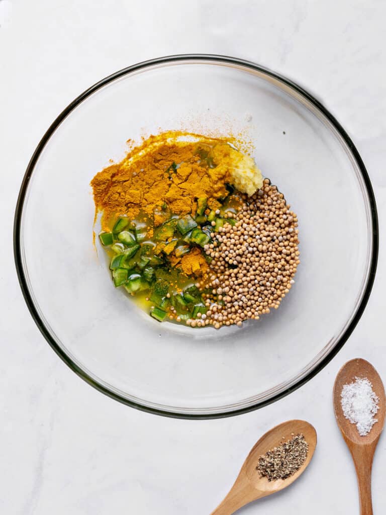 Ingredients for spicy mix for cauliflower bites in a glass bowl. Top view. Gray background.