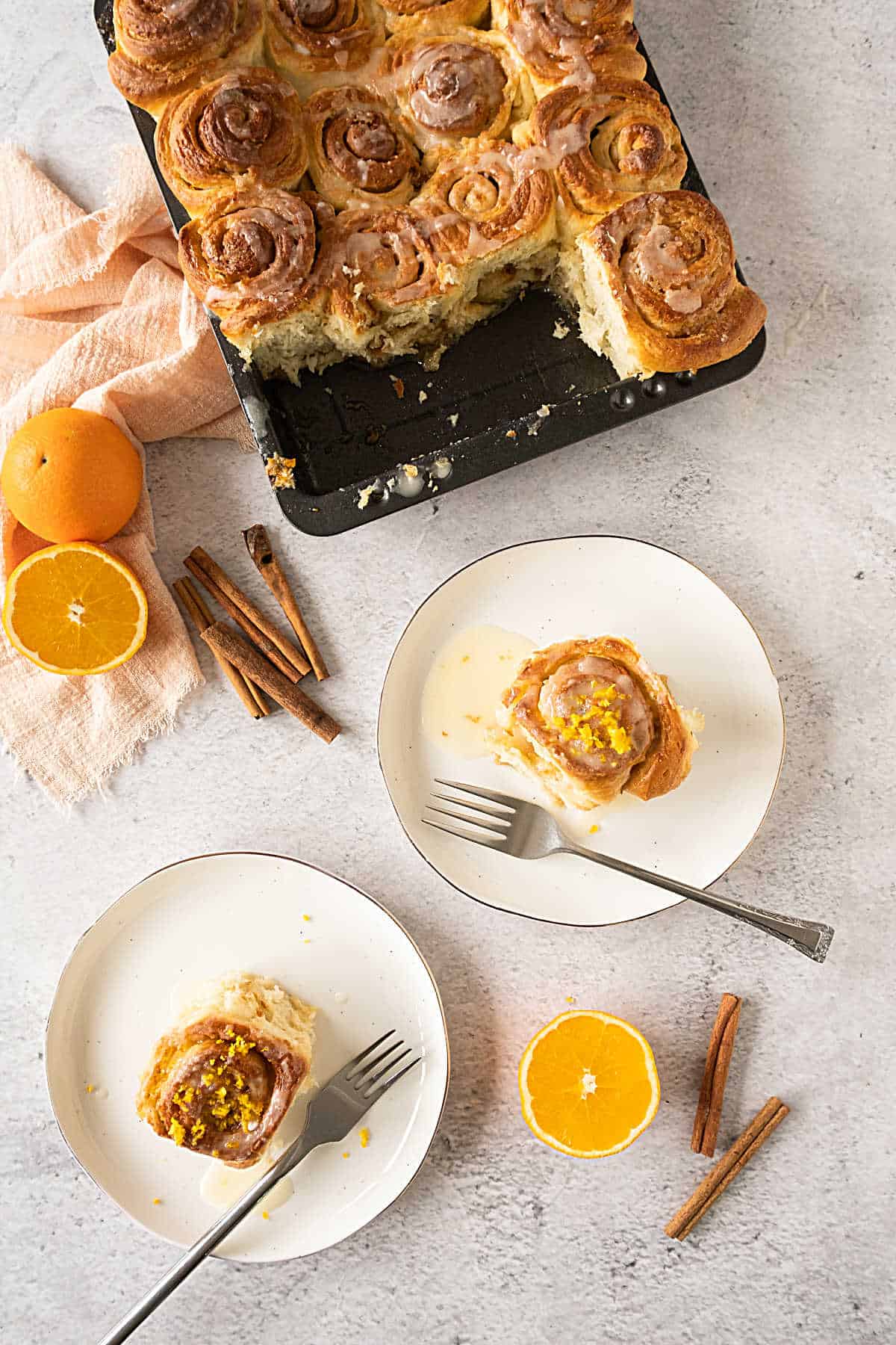 Top view of orange rolls in the black pan and served on white plates. Gray surface. 