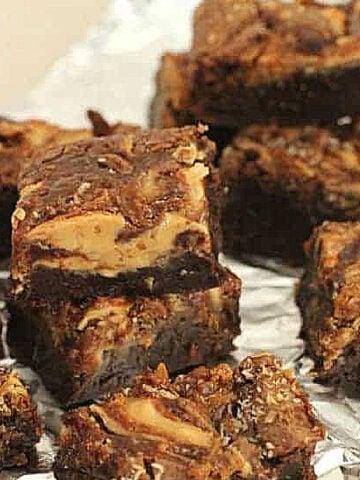 Stacked pieces of swirled brownies on aluminum foil.