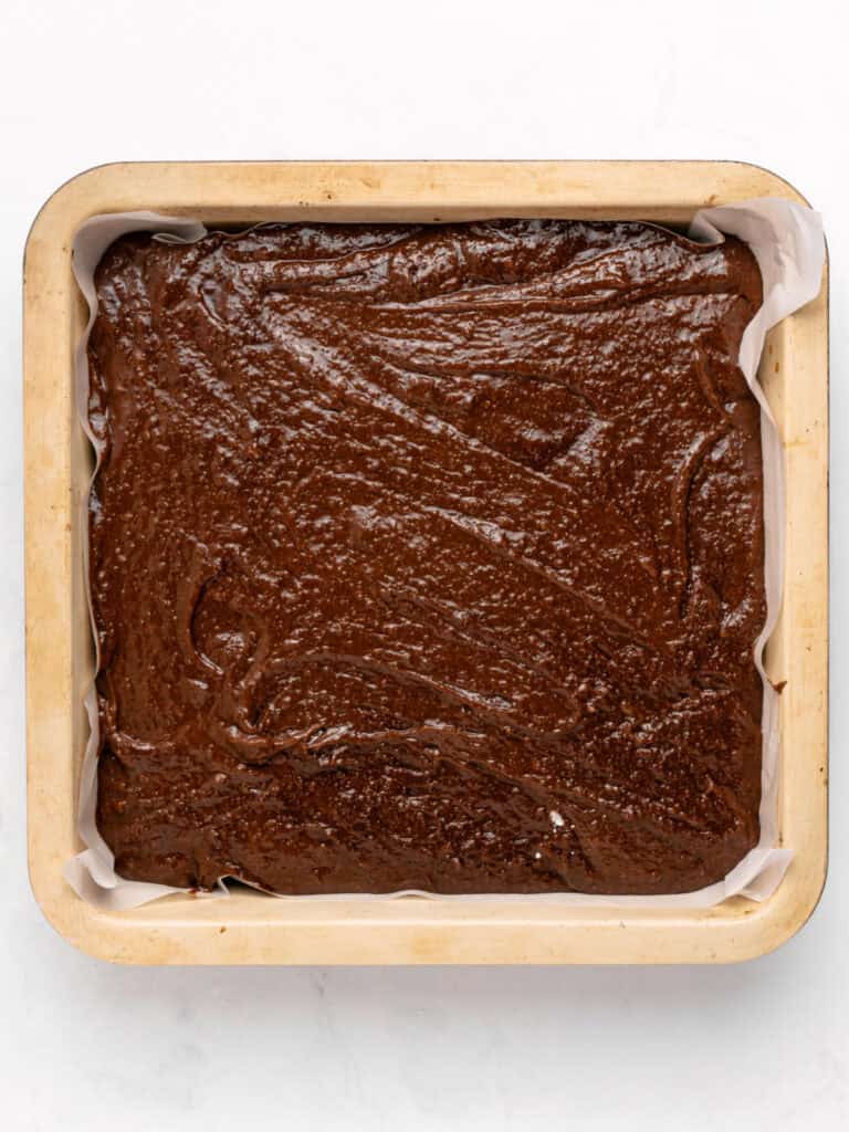 Square pan with brownie batter. White background.