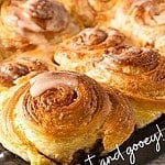Orange and white text overlay on close up of glazed orange rolls.