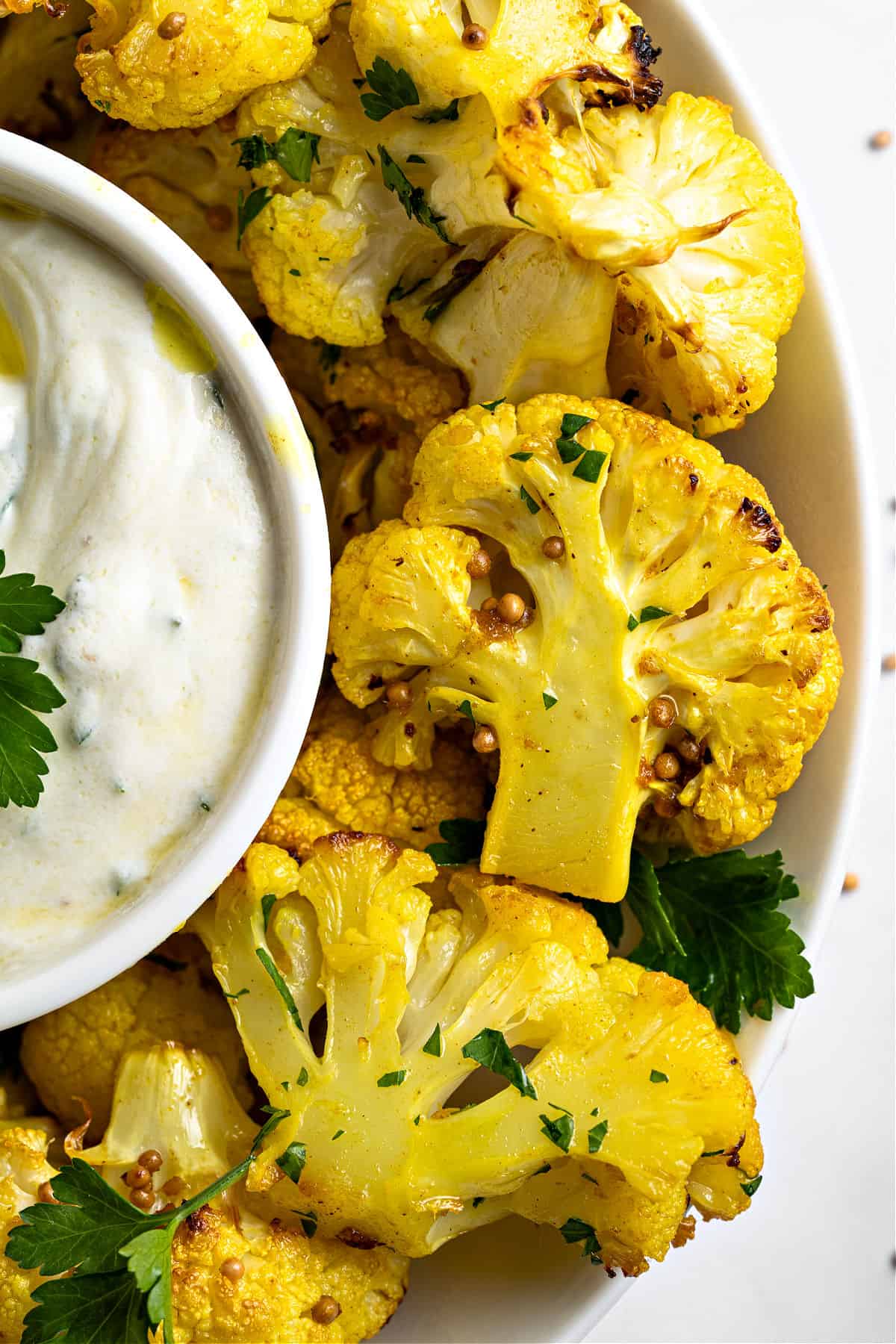 Close up bites of spicy cauliflower with yogurt dip. Partial top view.