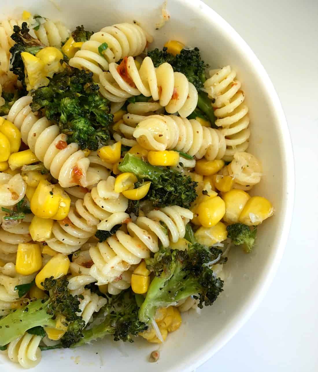 White bowl with broccoli corn harissa pasta 