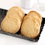 Metal tray with two rows of coconut shortbread cookies. White background.