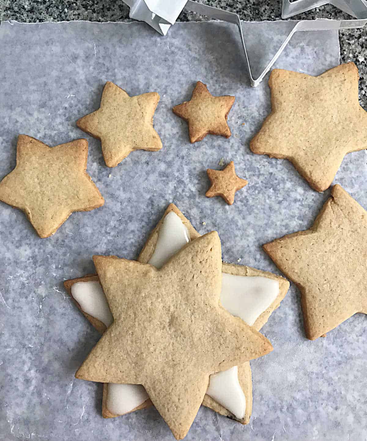 Several star shaped baked sugar cookies on whitish parchment paper