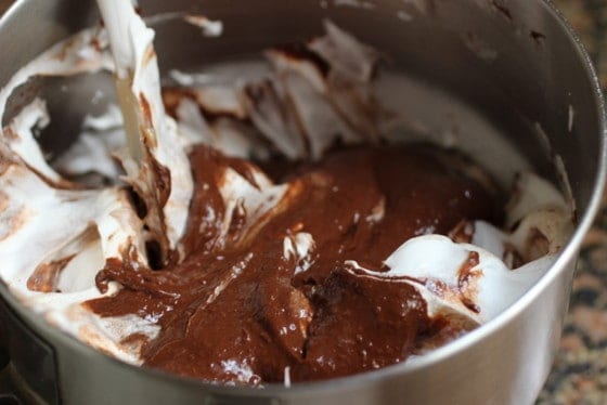 Mixing meringue with melted chocolate in metal bowl