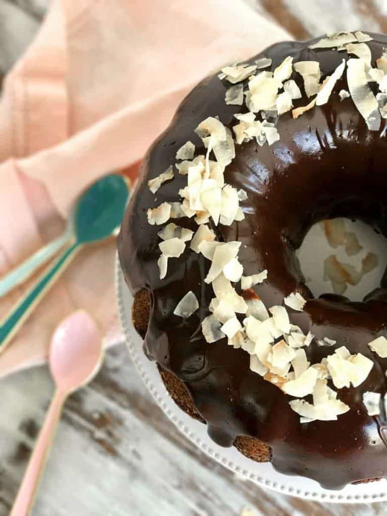 gedeeltelijke cake op standaard, roze servet, roze en aqua lepels, wit oppervlak