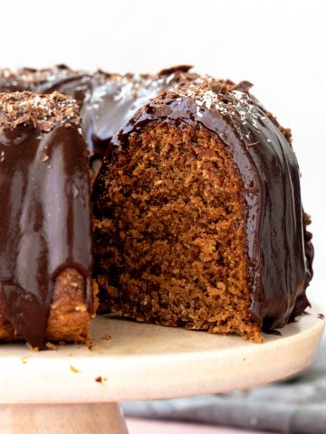 Slice of chocolate coconut cake, white surface, cake on cake stand, spoons