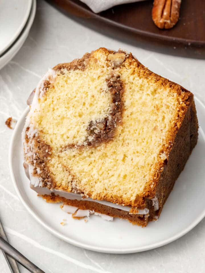 Single slice of cinnamon coffee cake on a white plate. Light grey surface.