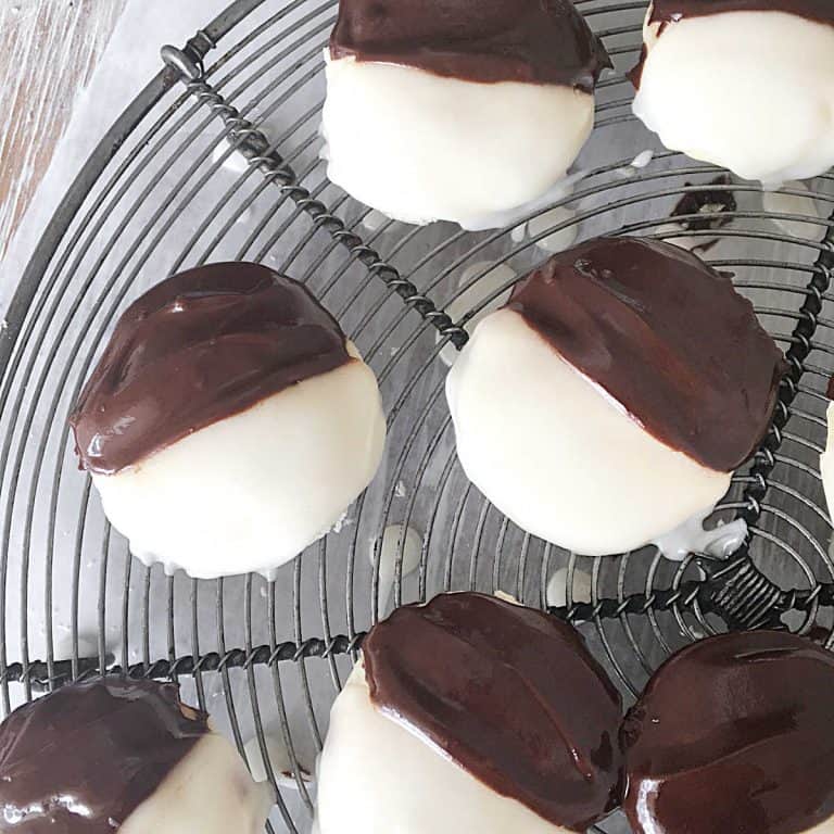 Several black and white cookies on a round wire rack. View from above.