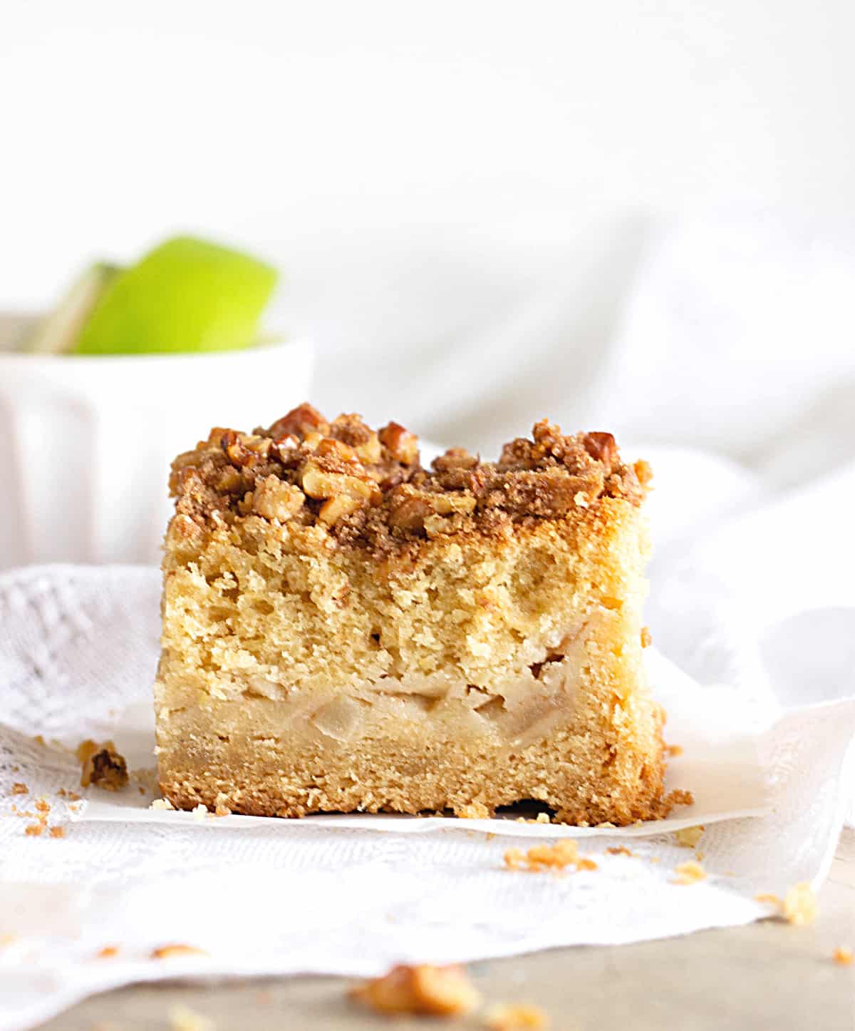 apple coffee cake Squares of Apple coffee cake, white surface, white bowl and green apples