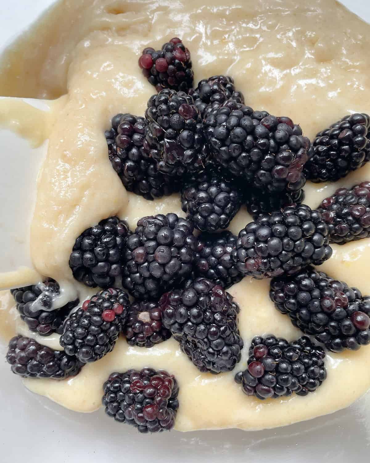 Fresh blackberries with muffin batter in a glass bowl.