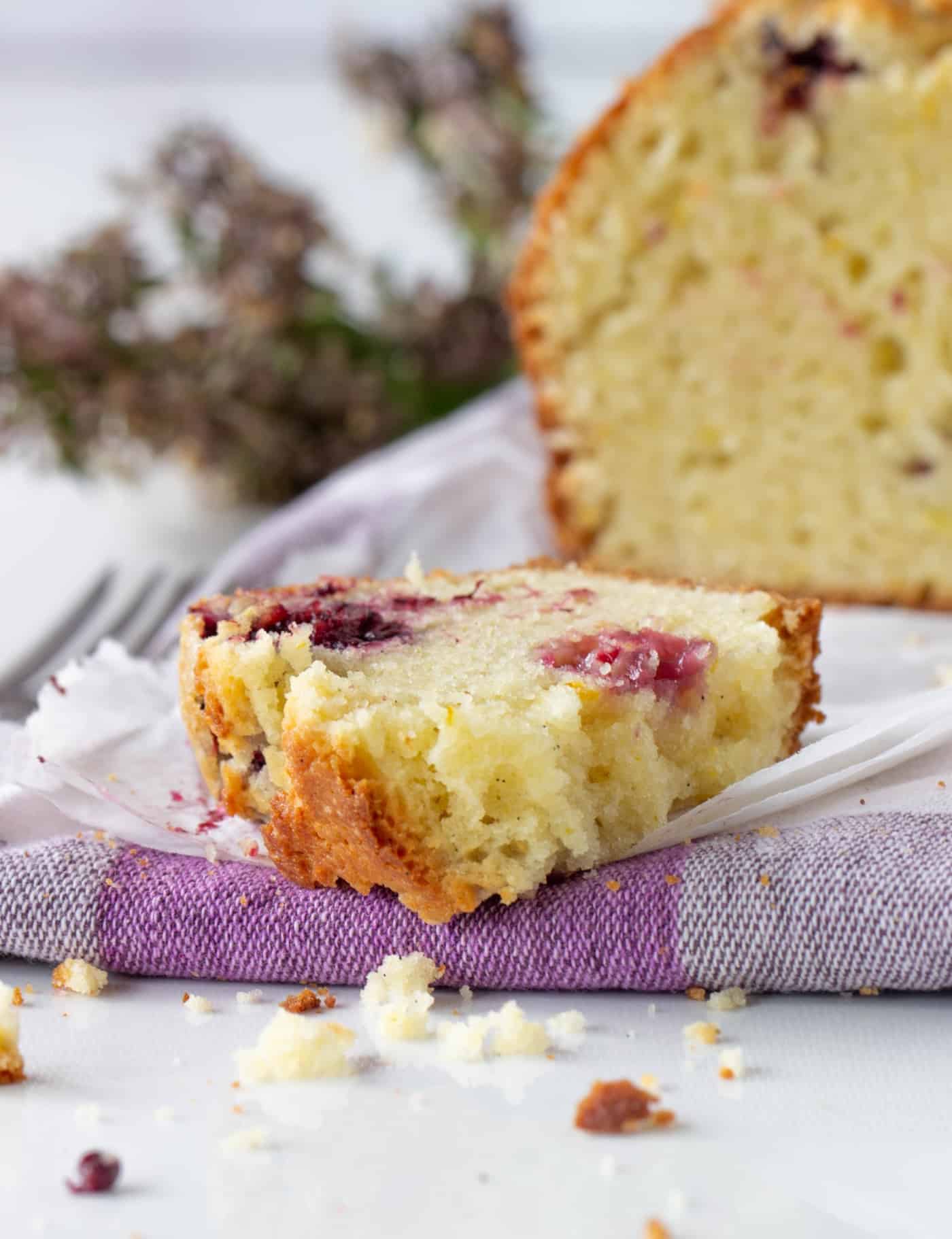 Close-up slice and loaf of Orange blackberry muffin cake, checkered kitchen cloth