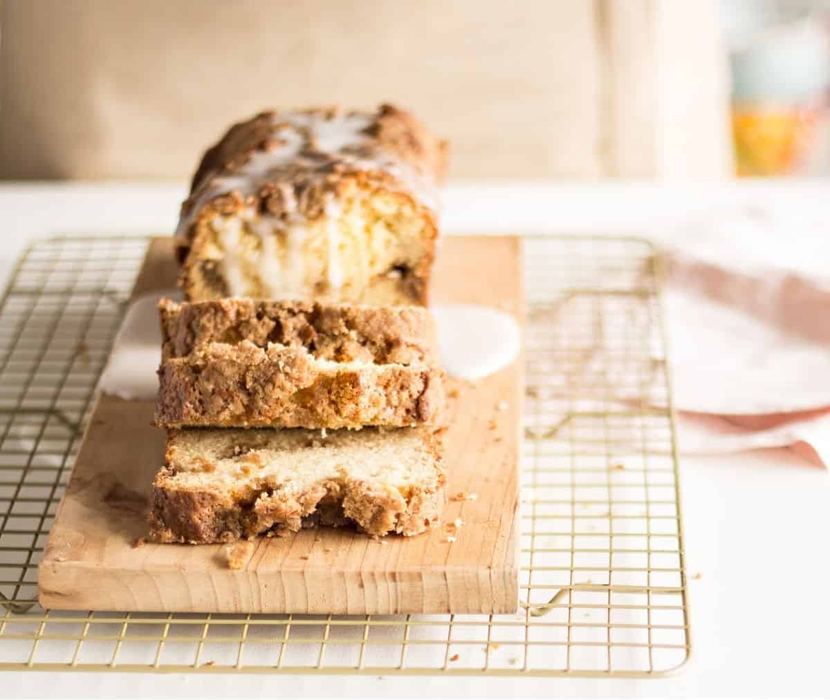 Metal rack with glazed coffee cake loaf on a wooden board, pink napkin beside it