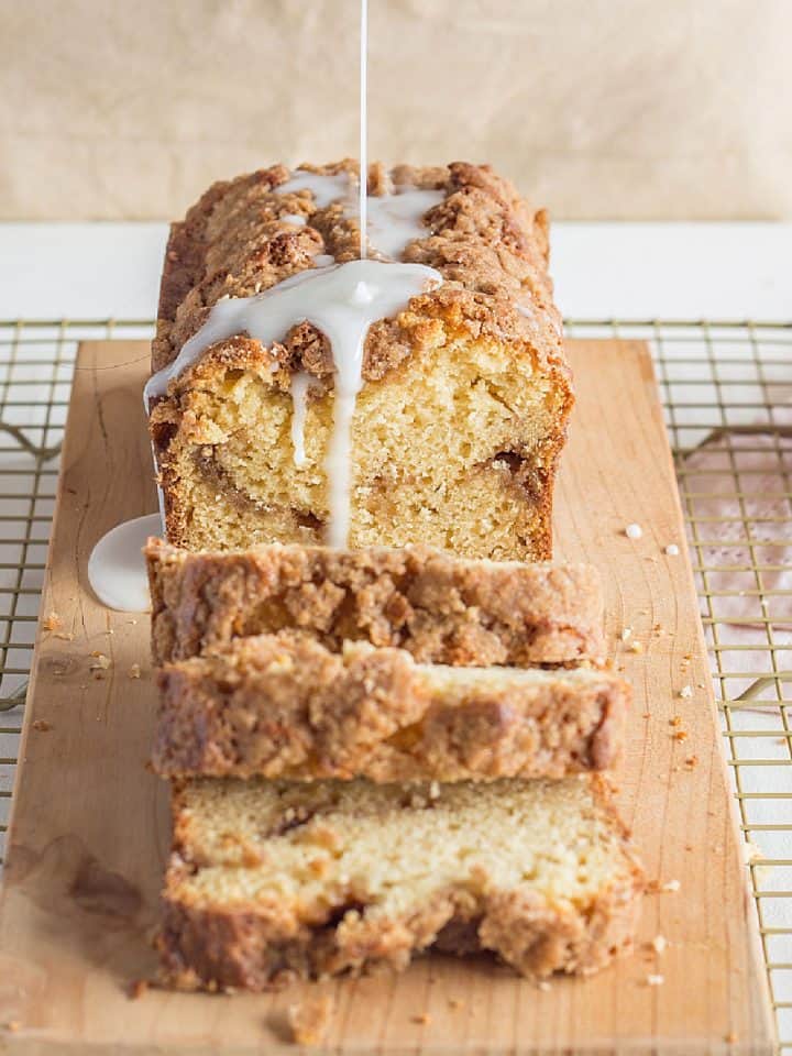 Glaze pouring over coffee cake loaf on a wooden board, metal rack