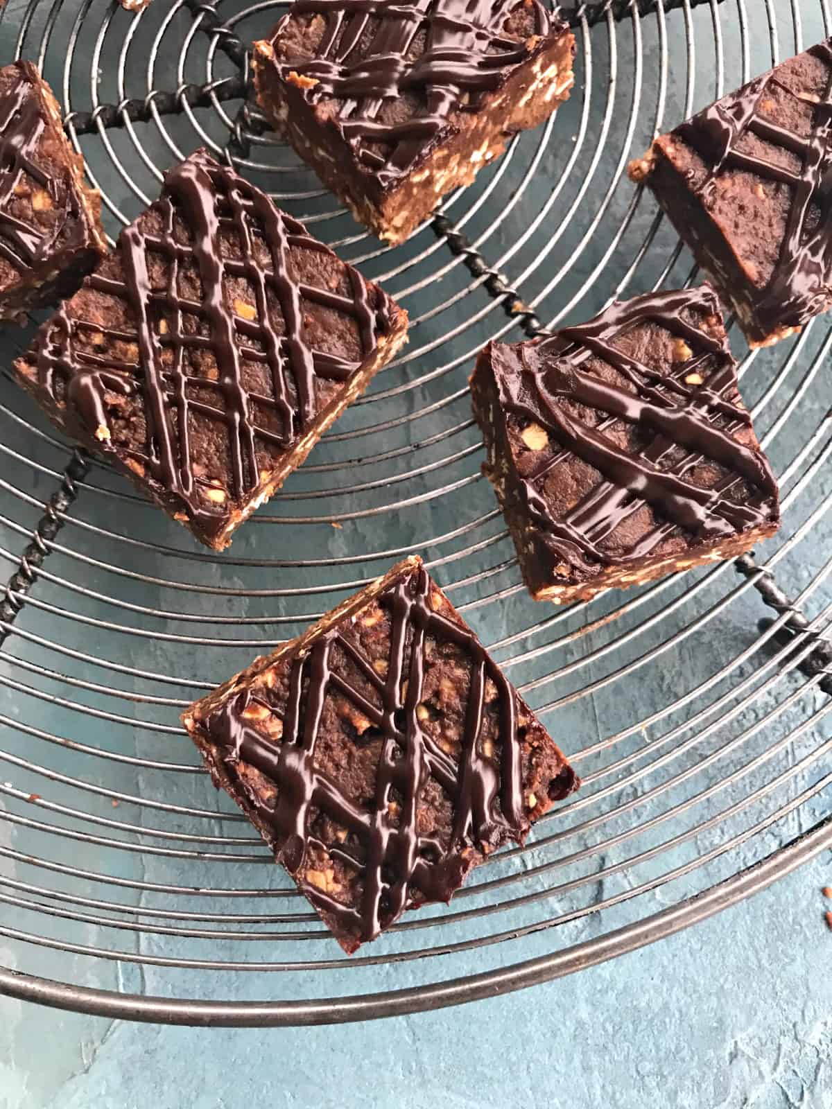 No-bake chocolate oat bars with ganache topping on a wire rack.