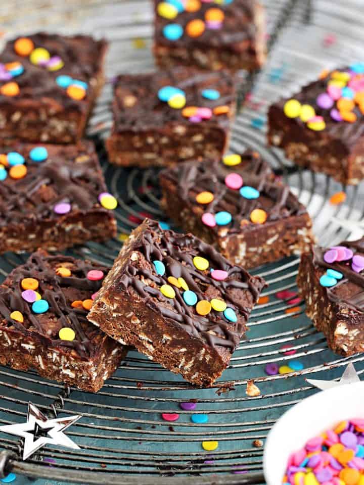 Chocolate oat squares on a wire rack with confetti, bluish background