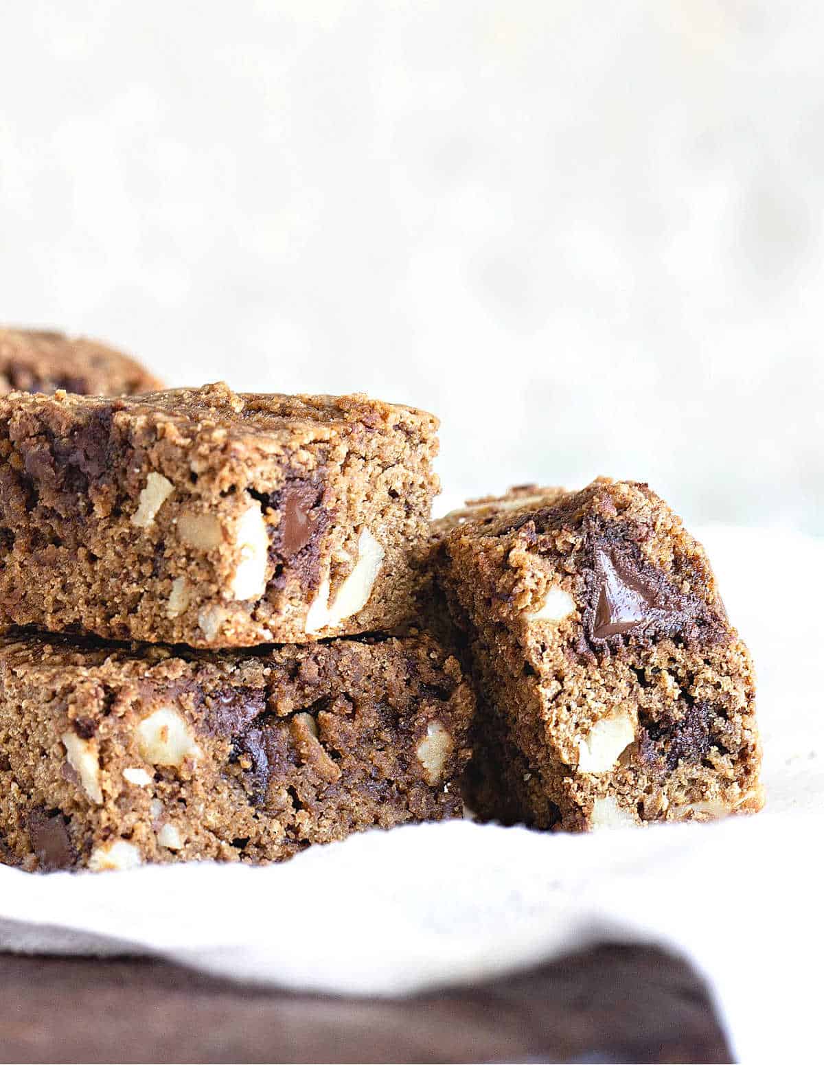 Stacked cookie blondie squares on a white cloth with white background. 