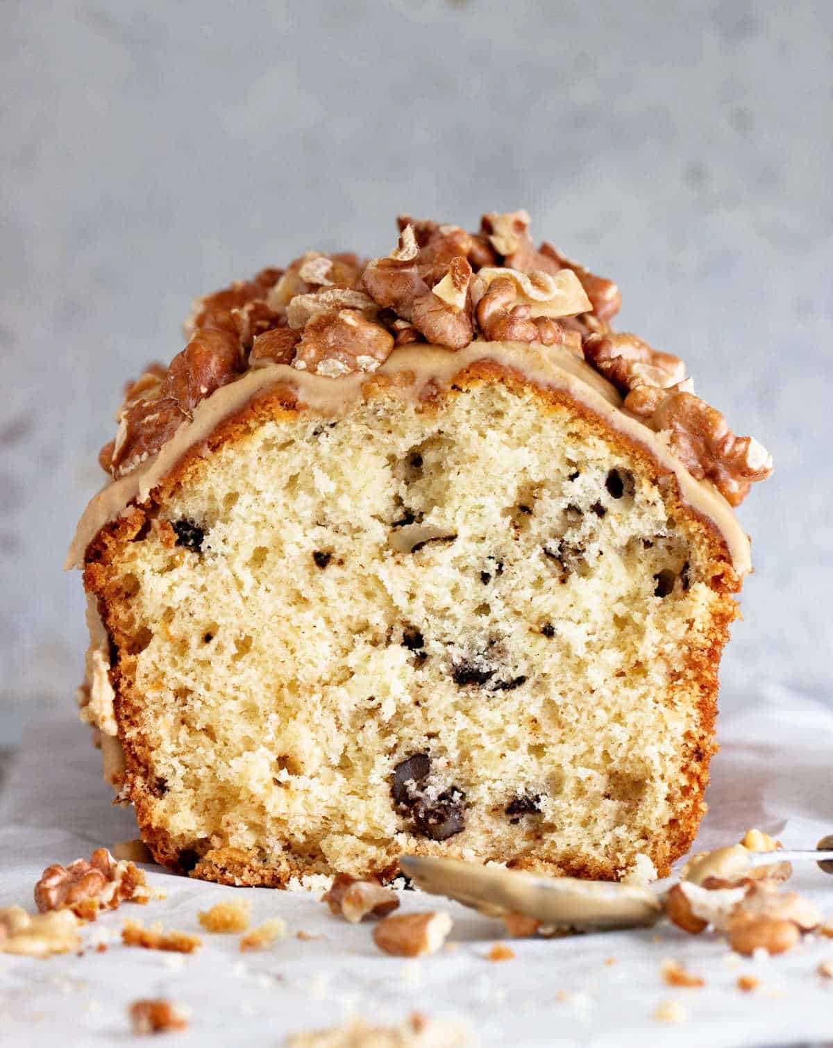 Walnut quick bread cut in half glazed with nuts. Grey surface and background. 