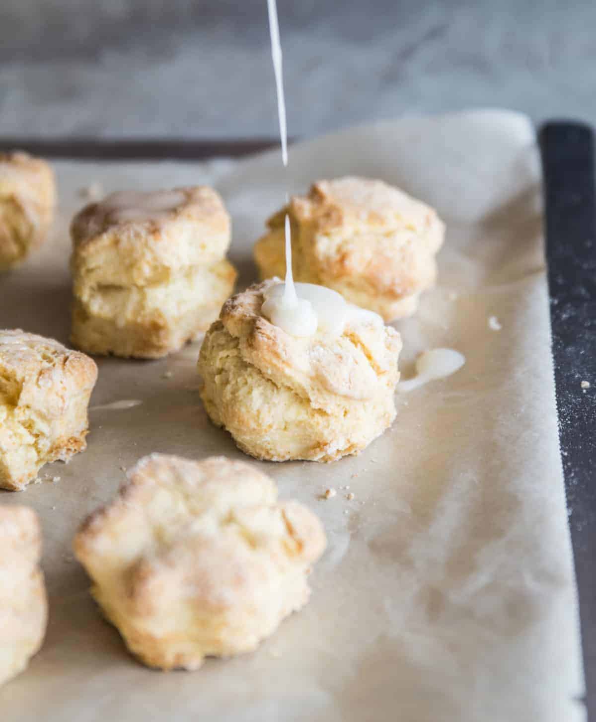 Tray of scones on parchmente paper, pouring glazed