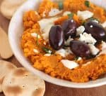 Bowl of carrot dip, black olives, goat cheese and crackers