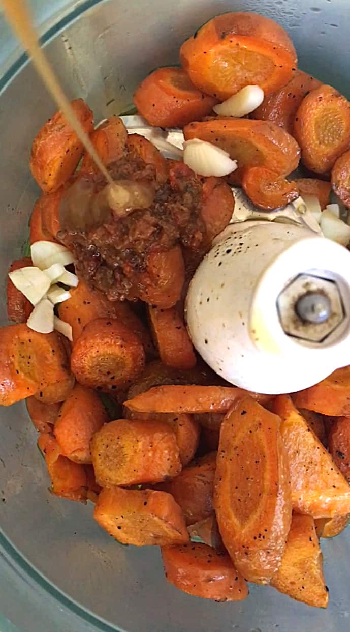 Roasted carrots, garlic, harissa and honey in bowl of food processor