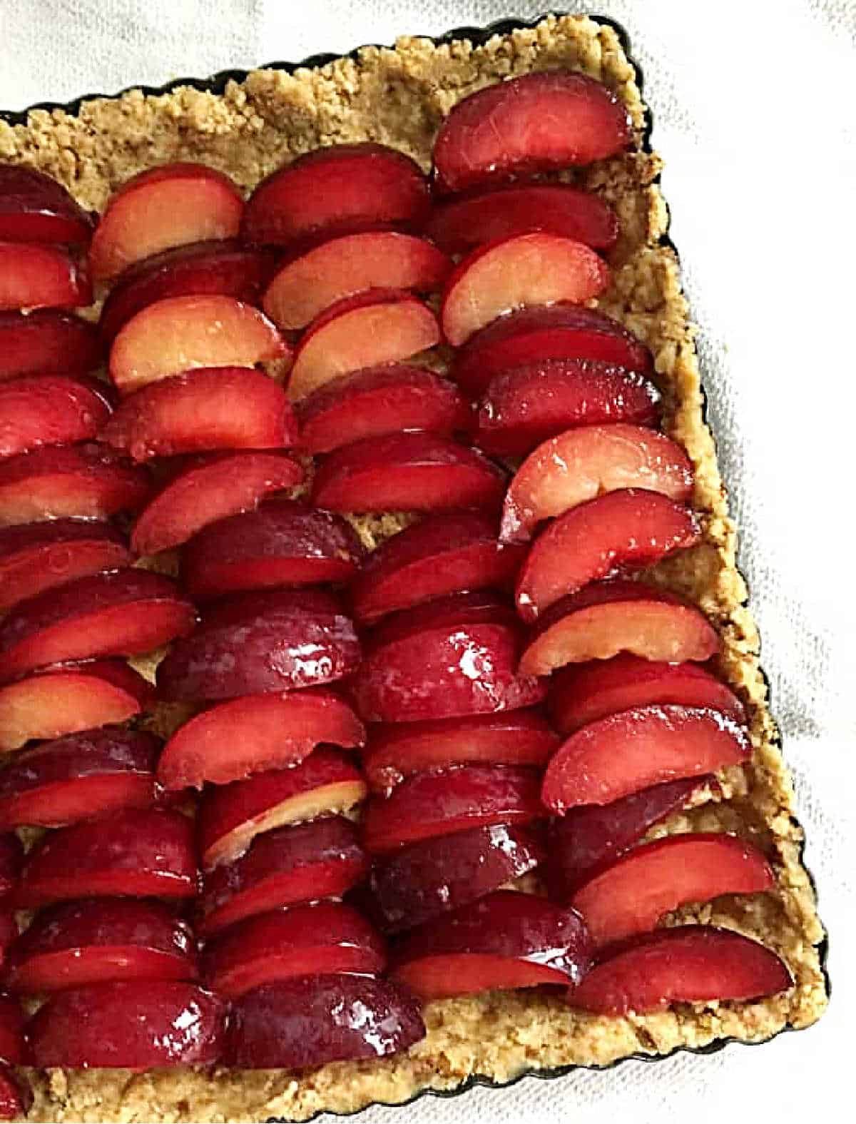 Overview of plum wedges packed in a crumb square crust