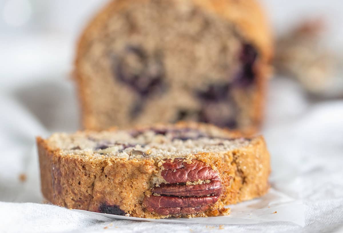 Close-up slice of blueberry pecan loaf, blurred background