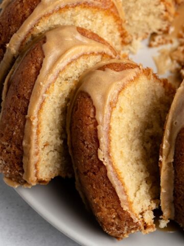 Close up glazed slices of butter bundt cake on a white plate.