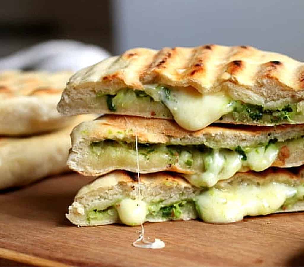 Stack of three filled grilled Naan Breads, oozing cheese on wooden board