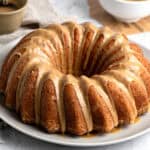 Whole glazed vanilla butter bundt cake on a white plate.