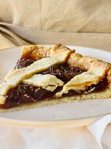 Single slice of lattice fig jam tart on a plate. Beige background.