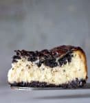 Slice of creamy Oreo Cheesecake on a cake server, grey background