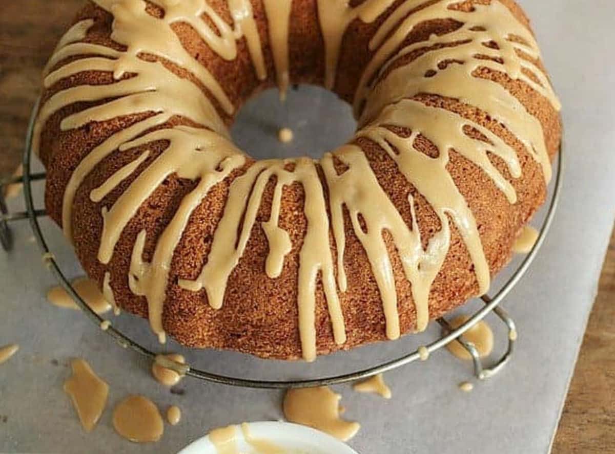 Whole bundt cake dripping with coffee glaze on a wire rack with parchment paper.
