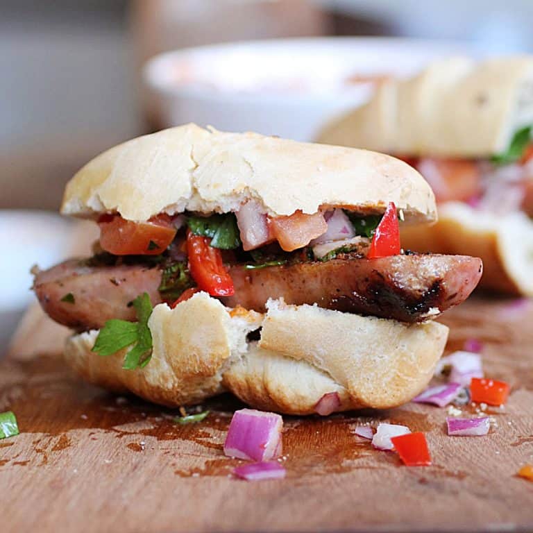 Wooden board with a chorizo sandwich with salsa.