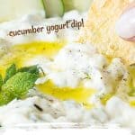 Red and white text overlay on close up image of cucumber yogurt dip with pita chip.